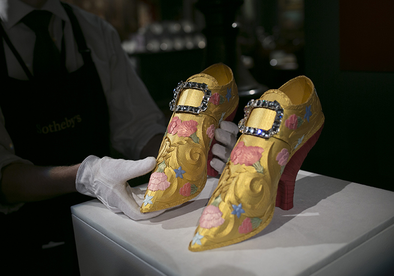 LONDON, ENGLAND - JANUARY 14: A gallery technician adjusts paper sculpture shoes adorned with Swarovski crystals. At Sotheby's on January 14, 2016 in London, England. (Photo by John Phillips/Getty Images for Sotheby's)